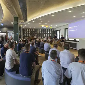 Publikum bei IT-Event mit Vortrag vor Präsentationsleinwand im Konferenzraum
