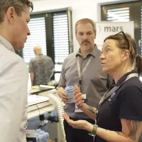 Frau im Gespräch mit zwei Männern auf Business-Event am Messestand mars