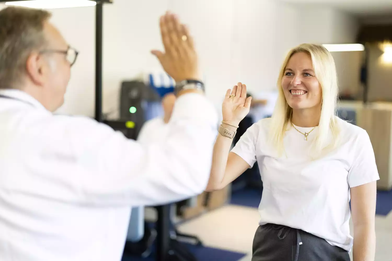 Lächelnde Mitarbeiterin gibt im Büro einem Kollegen ein High Five, Teamwork